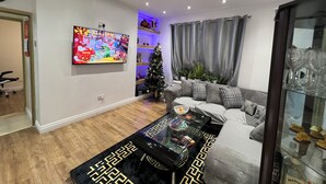 A modern living room with a flat-screen TV, a Christmas tree, a sofa, and a coffee table. - Fresh Apartment & Parking (London)
