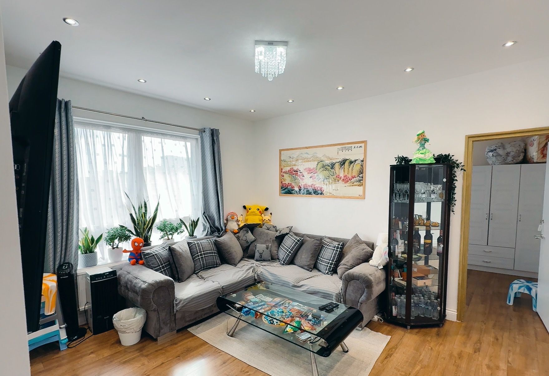 Un salon moderne avec un canapé d’angle, une table basse en verre et un meuble décoratif.