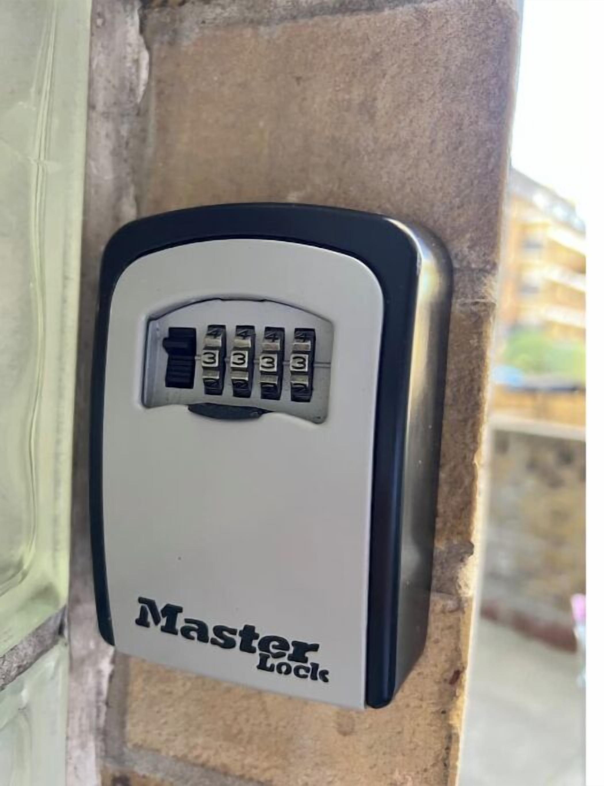 Un candado de combinación Master Lock fijado a una pared de piedra.
