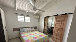 A bedroom with a bed, a ceiling fan, a washing machine, and a sliding door. - Residence La Terrasse (POINTE NOIRE)