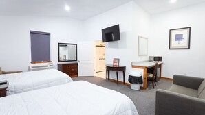 Une chambre d’hôtel avec deux lits, un bureau avec un ordinateur, une télévision et une chaise.