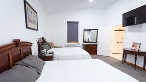Une chambre d’hôtel avec deux lits, un bureau, une commode, un miroir et une télévision.