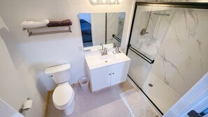 Une salle de bain comprenant des toilettes, un lavabo avec un miroir et un espace douche.