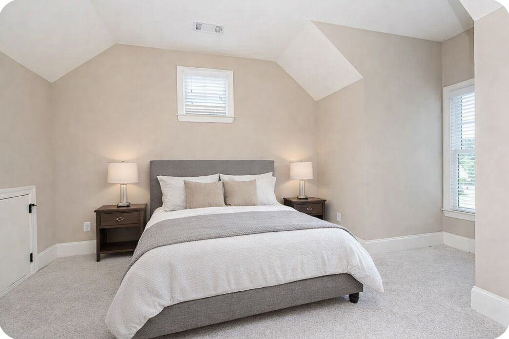 Une chambre à coucher avec un lit, deux tables de chevet, une fenêtre et un plafond en pente.