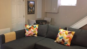 Una sala de estar con un sofá modular, dos almohadones estampados, una mesita redonda y un ventanal con vistas.