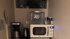 Una kitchenette compacta equipada con cafetera, microondas y refrigerador.