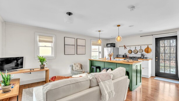 Een moderne keuken met een centraal eiland, een zithoek met een bank en een televisie op een standaard.