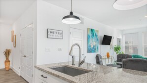 A modern kitchen with granite countertops, a stainless steel sink, and a pendant light.