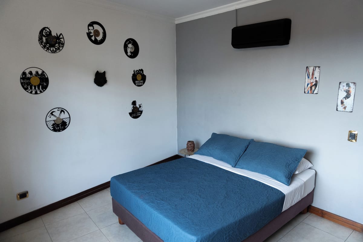 Une chambre à coucher comprenant un lit, une horloge murale et divers éléments de décoration, notamment des disques vinyle et une silhouette de chat.