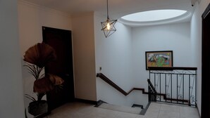 Un escalier avec une rampe, un tableau accroché au mur et un luminaire suspendu.