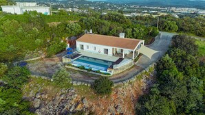 Une maison avec une piscine, un patio couvert et une vue sur une ville au loin.
