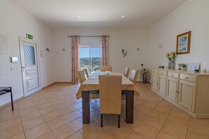 A dining area with a table, chairs, a cabinet, and a view through the window.