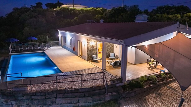 Une maison avec une piscine, un espace extérieur aménagé pour s’asseoir et une terrasse couverte.