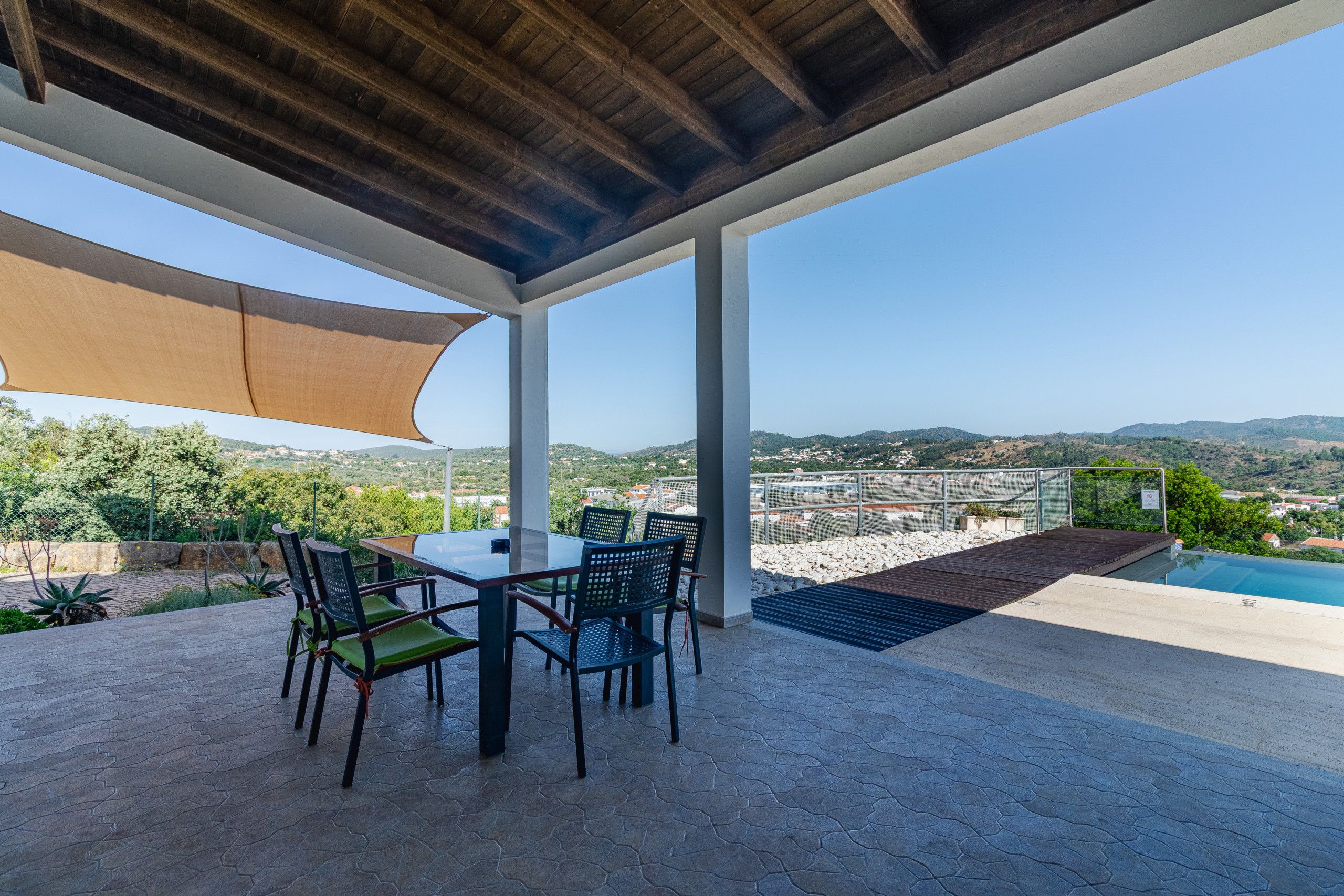 Eine Terrasse im Freien mit Tisch und Stühlen, einem Pool und Blick auf die Landschaft.