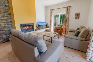 A living room with a fireplace, sofas, a coffee table, and a television.