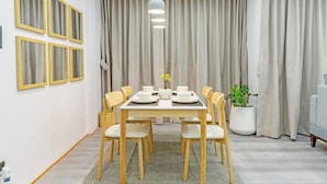 Un coin repas avec une table en bois, six chaises et un lustre.