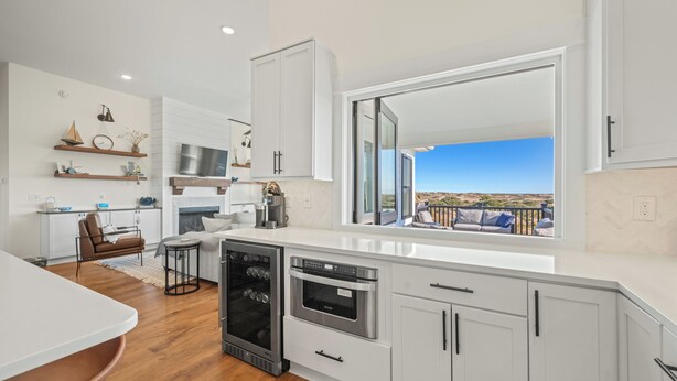 A modern kitchen with white cabinetry, a large window, and a view of the outdoors. - Wags & Waves: Sept. 18th Wk Reduced, Fri-Fri, Dog-friendly, Walk to Beach (Corolla)