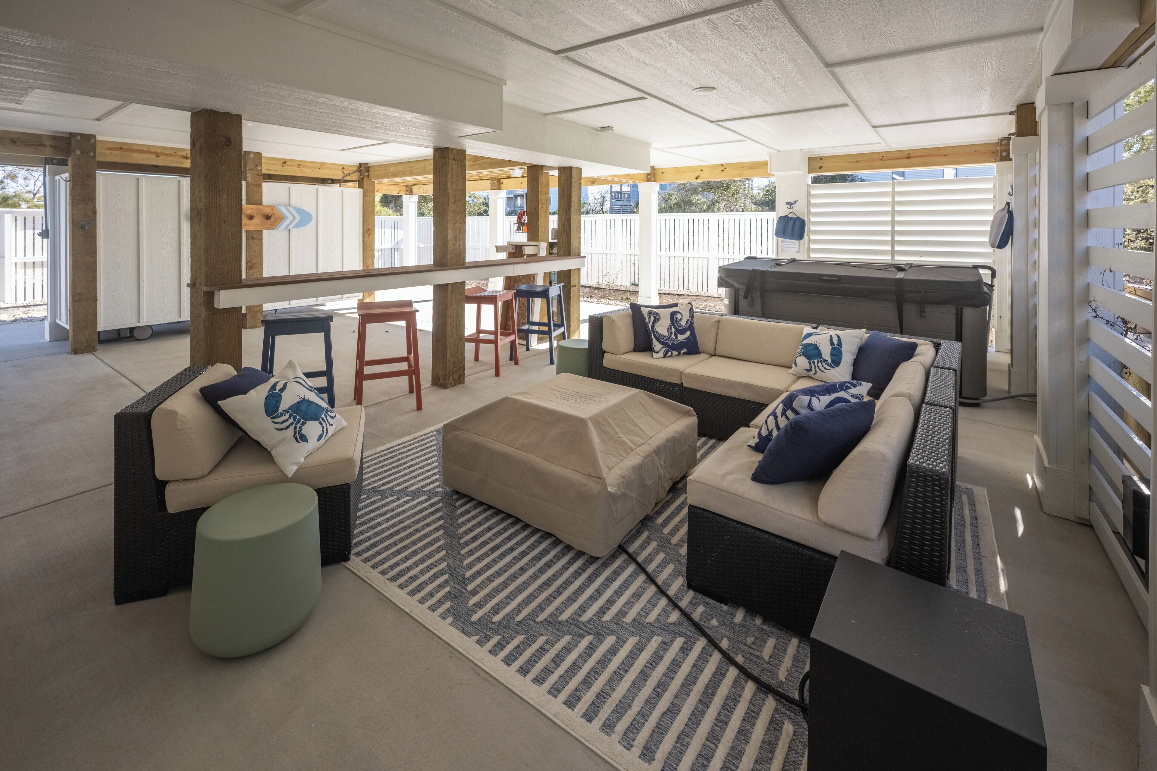A covered outdoor living area with a sofa set, a bar area, and a grill.