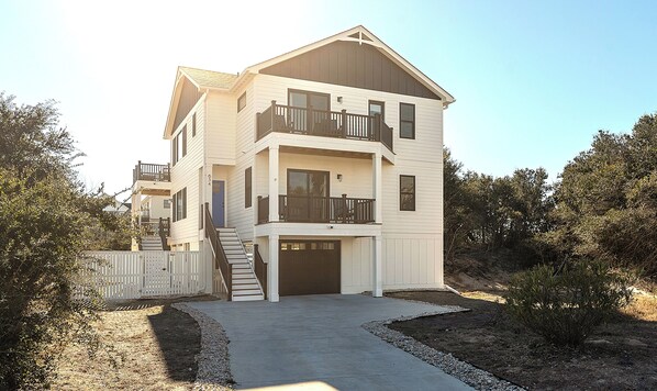 A two-story house with a front entrance, a balcony on the second floor, and a garage.