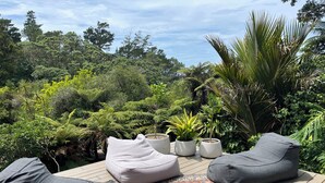 Une terrasse avec des sièges d’extérieur, un tapis à motifs et des plantes en pot.