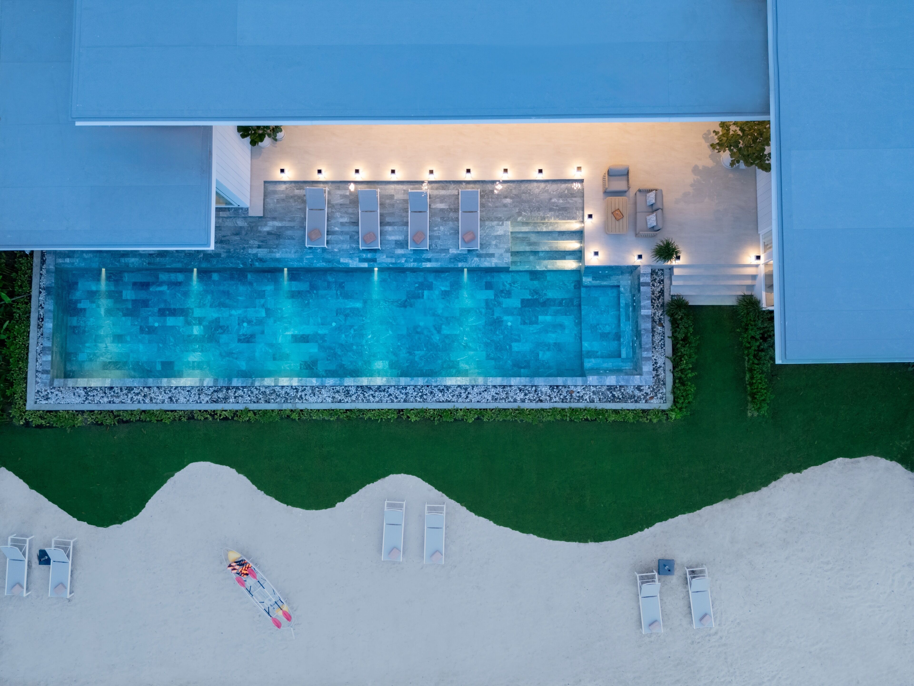 Vista aérea de una piscina con sillas de descanso y una zona de terraza.