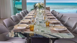 A long dining table set for a meal with a view of the ocean. - Villa AMANN (Kamala)