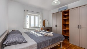 A bedroom with a bed, a bedside table, a mirror, a wardrobe, and a window.