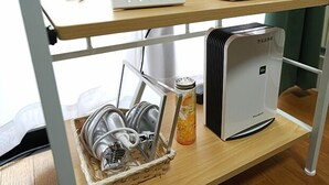 Un coin cuisine comprenant un égouttoir à vaisselle, un distributeur d’eau et une machine à café, le tout placé sur une étagère en bois.
