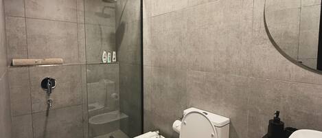 Ein modernes Badezimmer mit Duschkabine aus Glas, Toilette und Waschbecken.