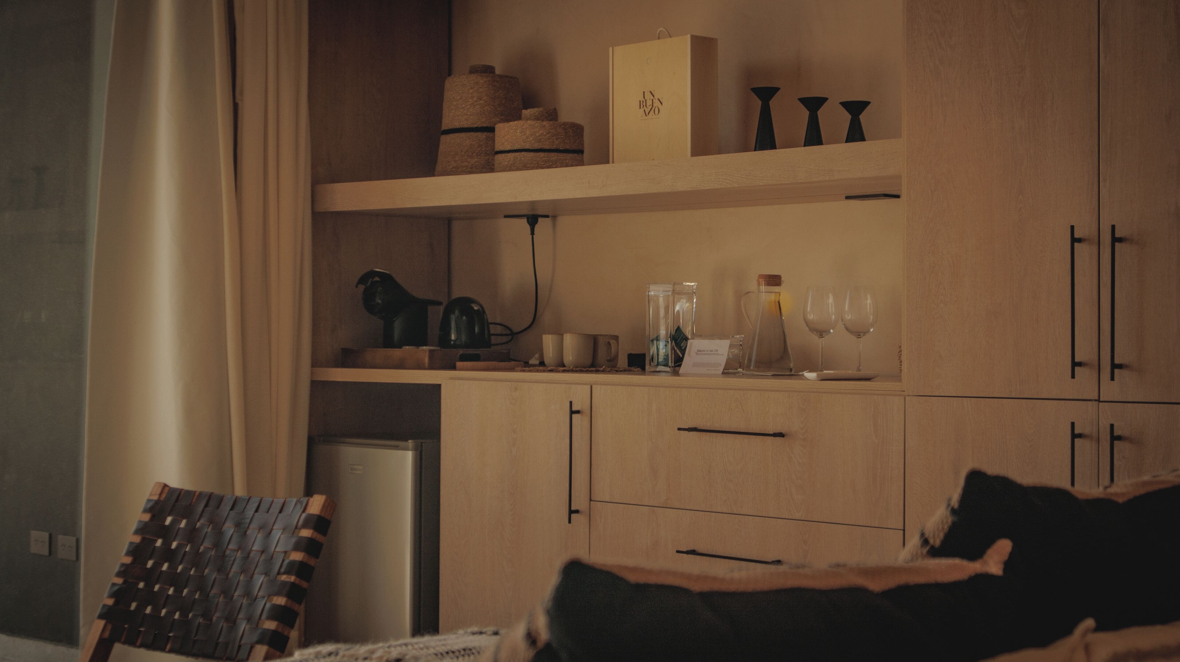Una habitación acogedora con una cama, una silla, armarios de madera y una cafetera.
