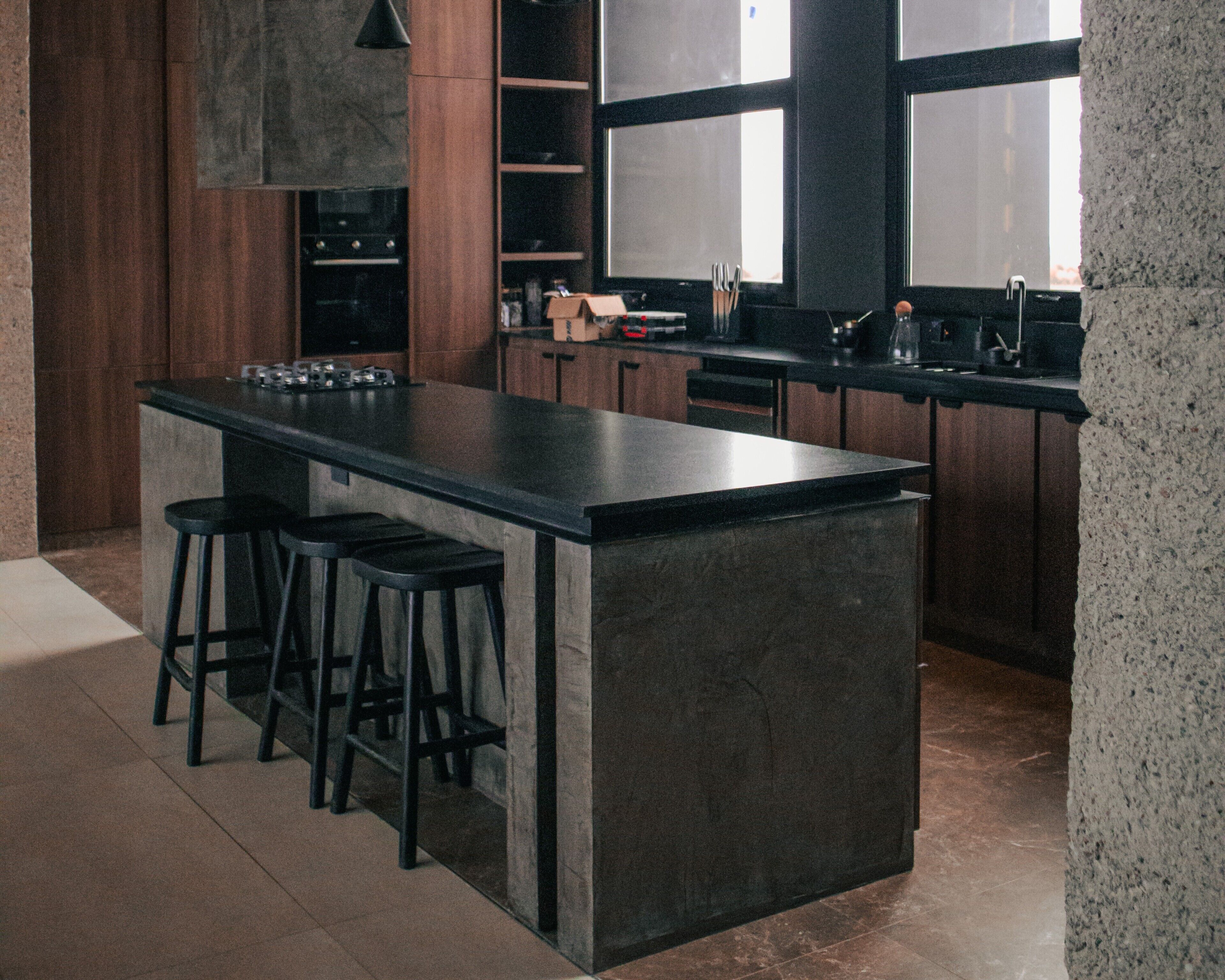 A modern kitchen with a large island, bar stools, and a built-in oven.