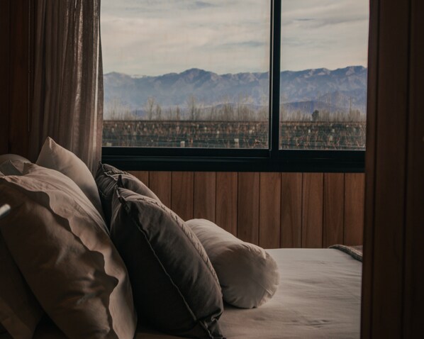 Un lit avec des oreillers et une vue sur les montagnes par la fenêtre.