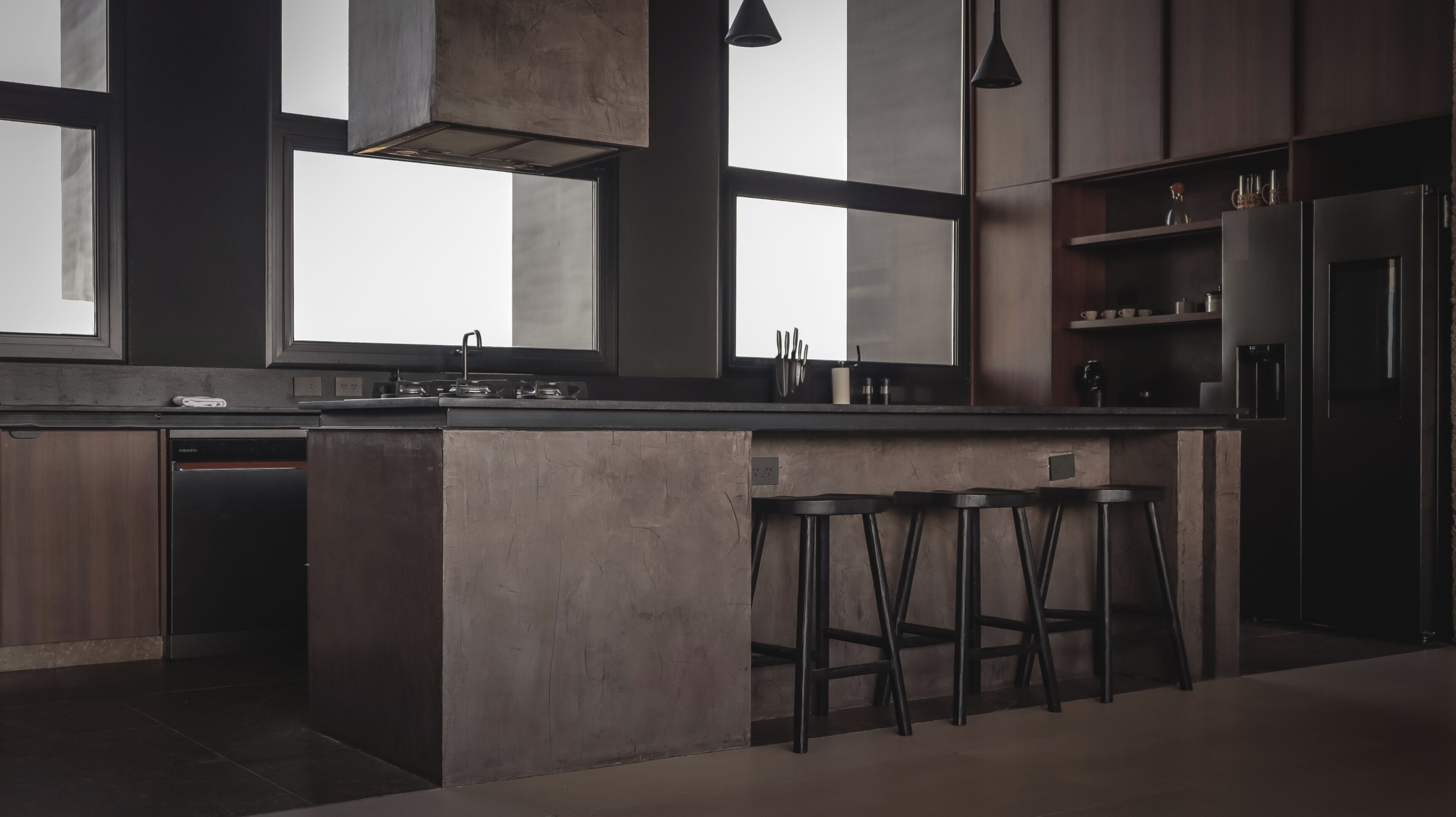 Una cucina moderna con isola centrale, sgabelli da bar e forno integrato.