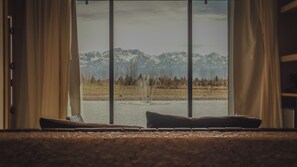 A room with a large window overlooking a mountainous landscape, a bed with pillows, and a small table. - Finca Boutique Un Buen Año (Eugenio Bustos)
