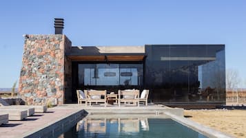 Una piscina al aire libre, sillones reclinables de piscina