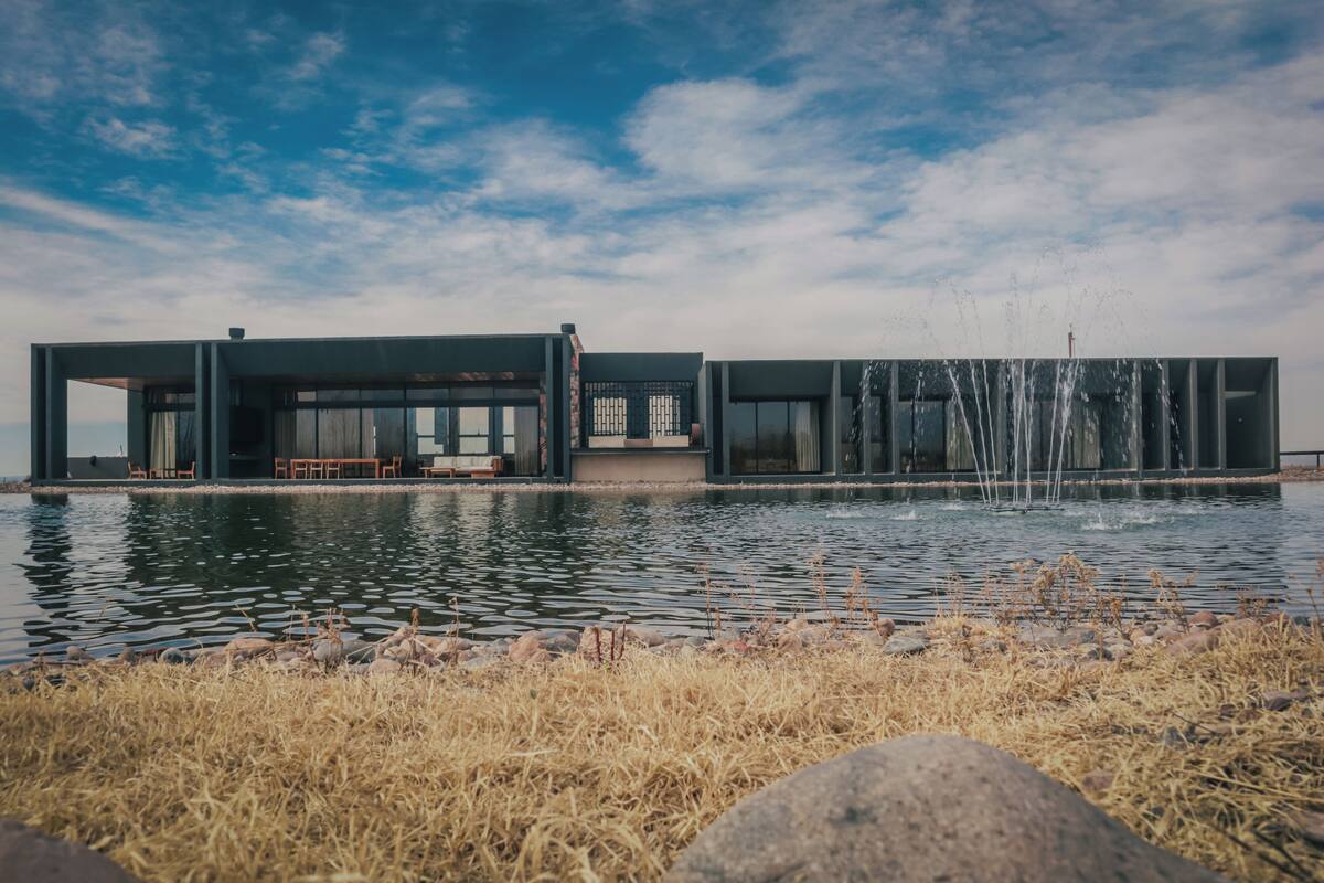 A modern building with large windows, a pool, and a fountain.