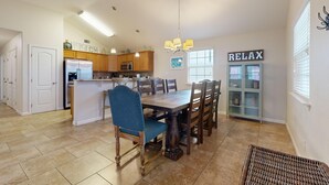 Una cocina amplia con armarios de madera, una isla central y un comedor con una gran mesa y sillas.