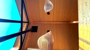 Una habitación con paredes y techo de madera, un tragaluz y dos lámparas colgantes.