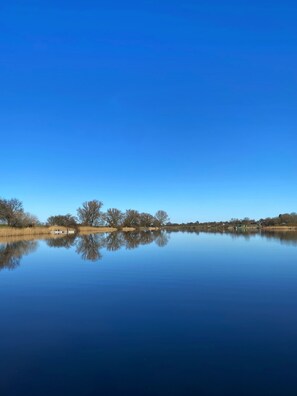 A calm lake with a clear reflection of trees and a boat.