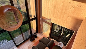 Un interior moderno con ventanas amplias, un conjunto de sofá y una lámpara colgante.