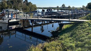 A marina with boats docked, a small bridge, and a grassy area.