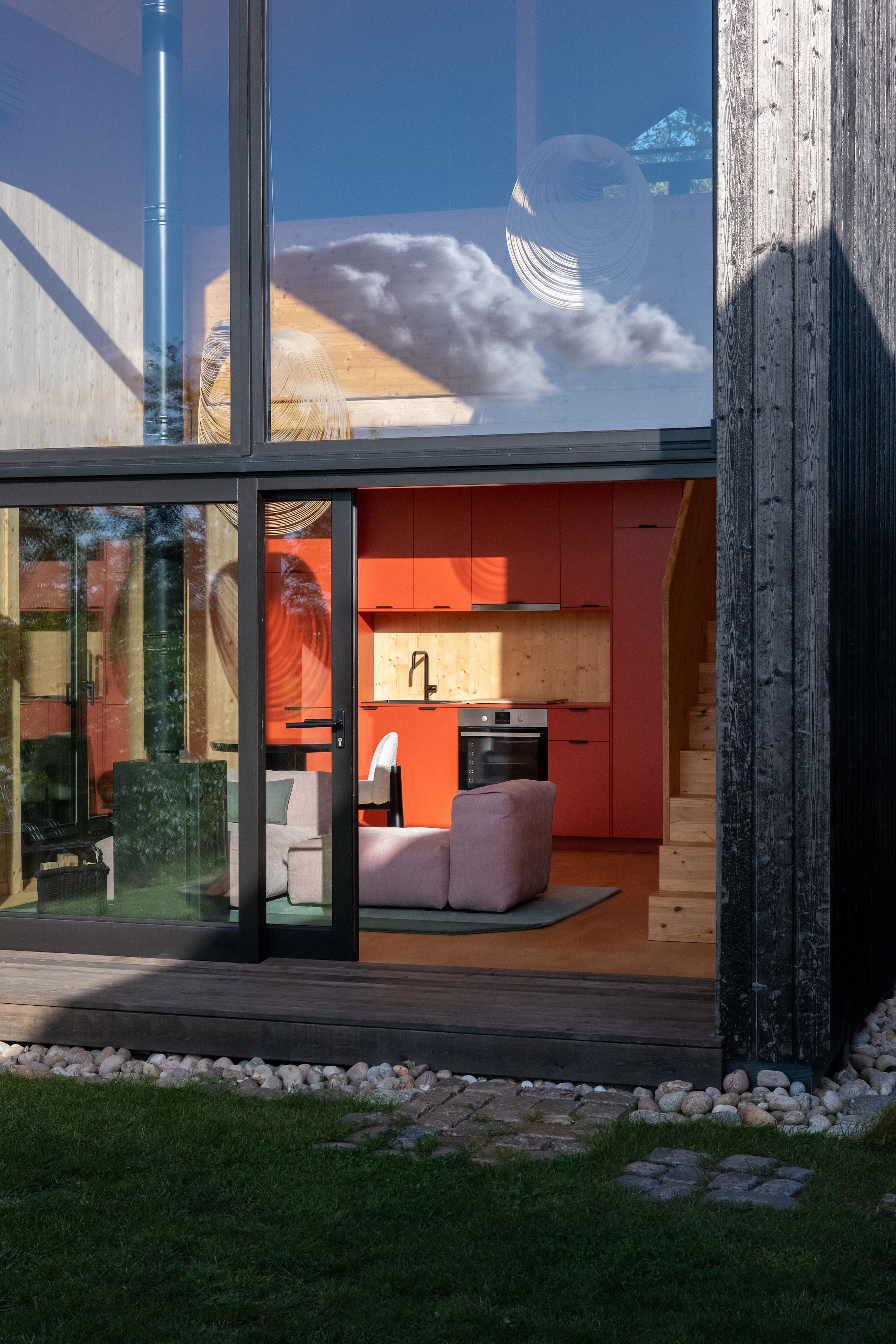 Eine moderne Küche mit roten Schränken und einem großen Fenster mit Blick auf einen Garten.