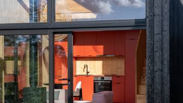 Eine moderne Küche mit roten Schränken und einem großen Fenster mit Blick auf einen Garten.