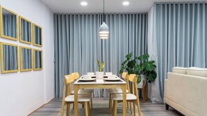 Un'area pranzo moderna con tavolo in legno, sei sedie e un lampadario centrale.