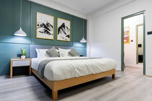 A modern bedroom with a wooden bed, a nightstand, a potted plant, and two wall-mounted pendant lights. - Modern 2 Bedroom Apartment in Putalisadak, Kathmandu (Kathmandu)