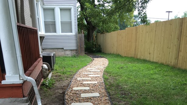 Un sentier bordé de pierres plates qui mène à une maison.