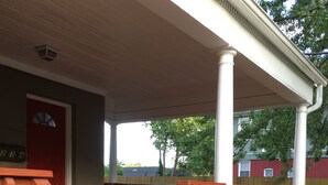 Une véranda en bois avec un banc et des plantes en pot.