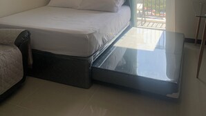 Et hotelværelse med en seng, ventilator, et ur, udsigt til det fri og en balkon.