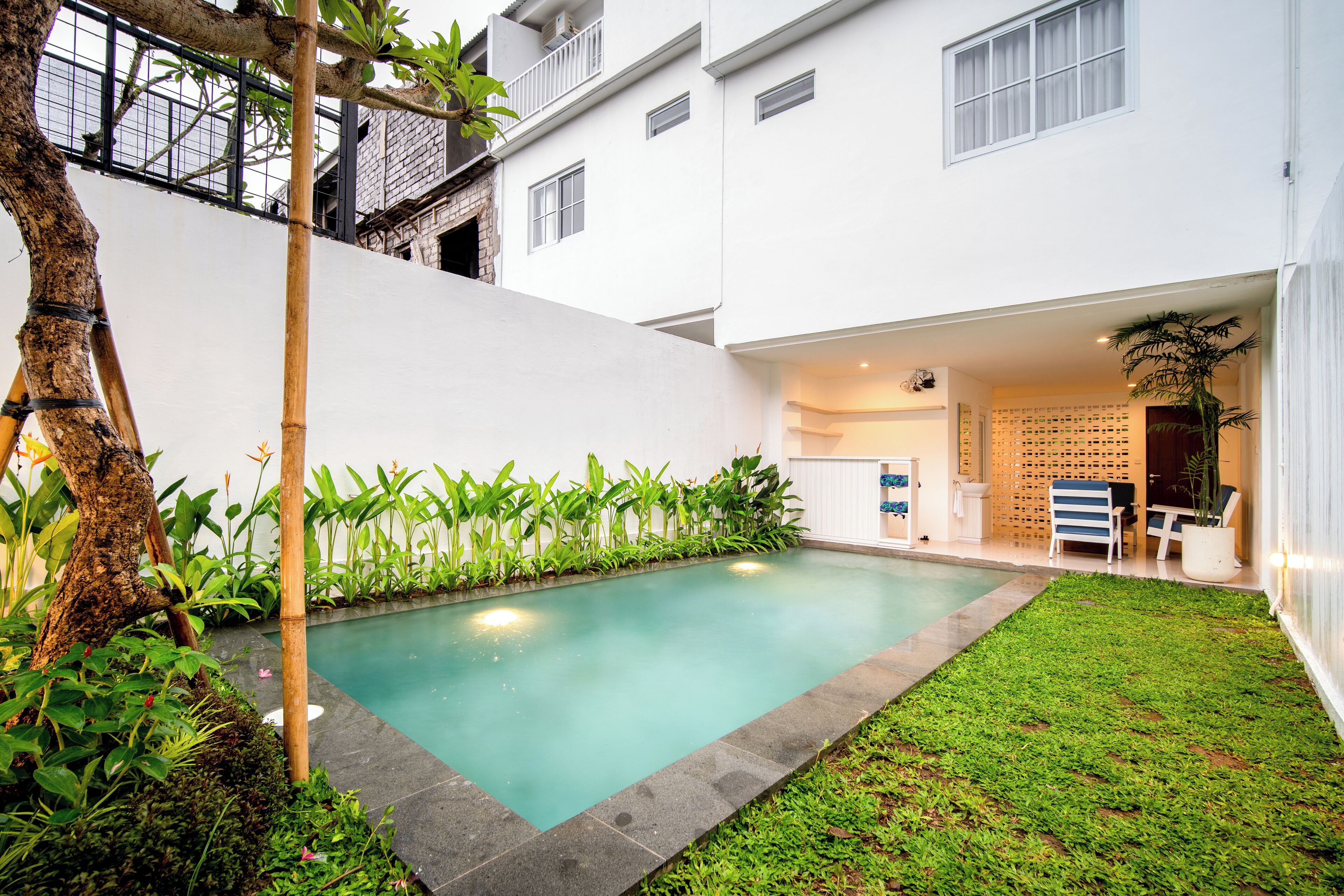 A modern residential building with a swimming pool, a small garden, and a balcony.