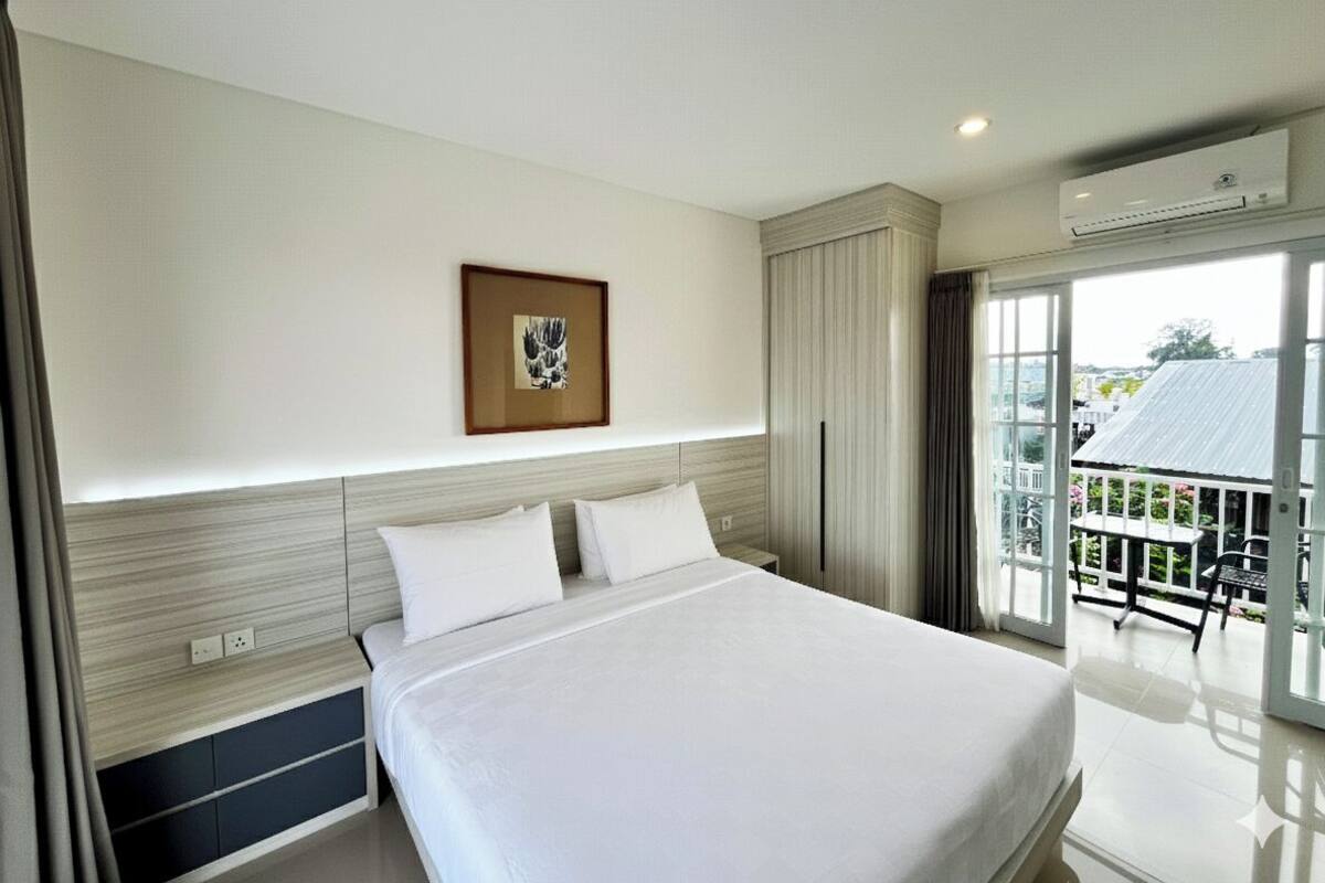 Habitación de hotel moderna con una cama grande, una obra de arte enmarcada en la pared y un balcón con vistas.